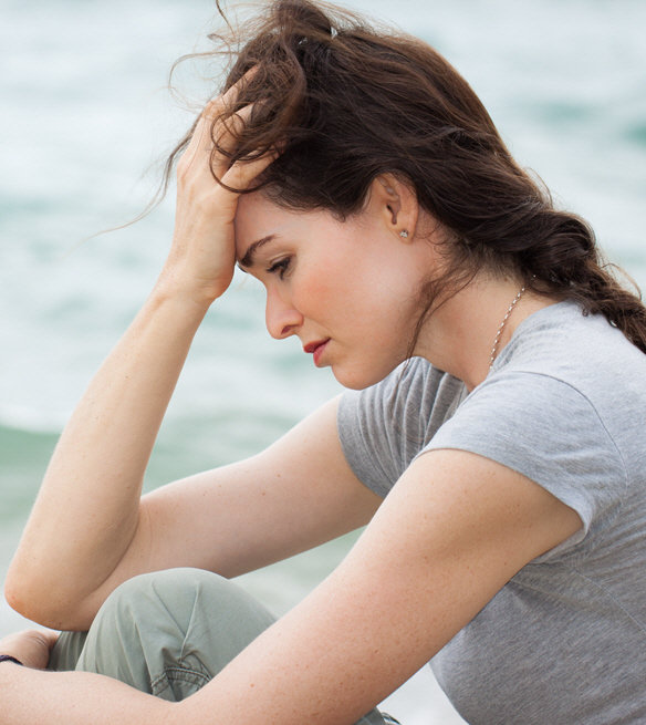 Woman sitting with her head resting on her hand, looking tired and overwhelmed